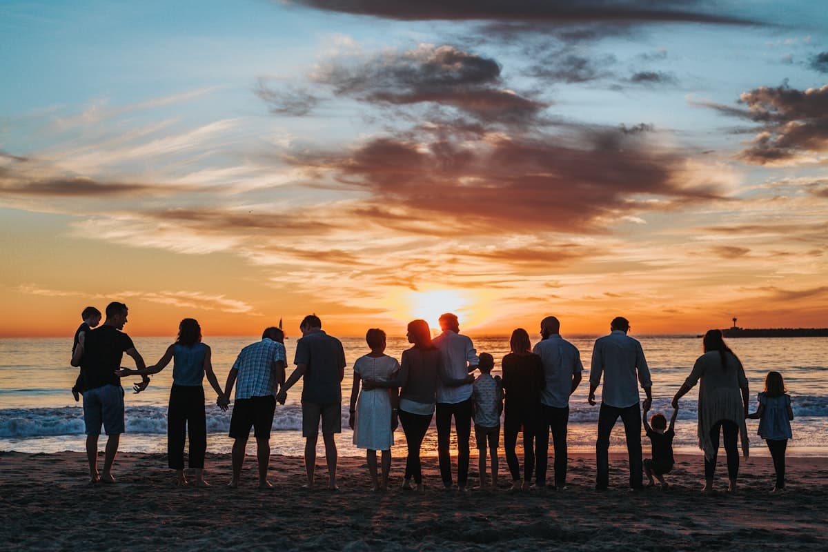 Familie steht bei Sonnenuntergang gemeinsam am Strand